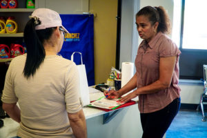 A worker at Sanchez Laundry Center, 401 Hartford Ave., Providence, speaks with Clara Diaz about the Central Providence Loan Fund.