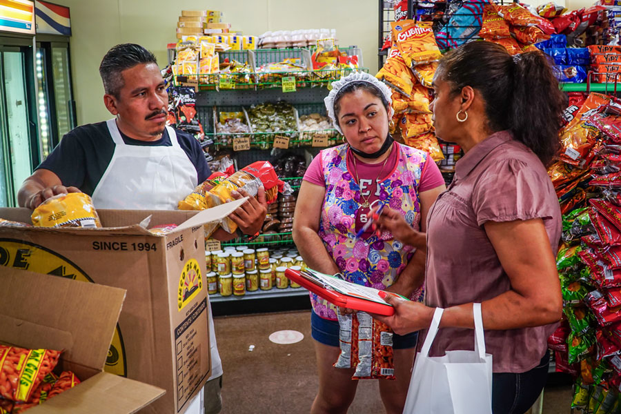 At Panaderia El Quetzal, 445 Hartford Ave., Providence, Clara Diaz leaves information about the Central Providence Loan Fund after speaking with Evelin & Elder Lopez.