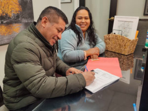 Fredy and Ana Jimenez sign paperwork at the closing on Dec. 16, 2022, for their home on Amherst Street in Providence. Photo by Antonio A. Rodriguez/ONE Neighborhood Builders