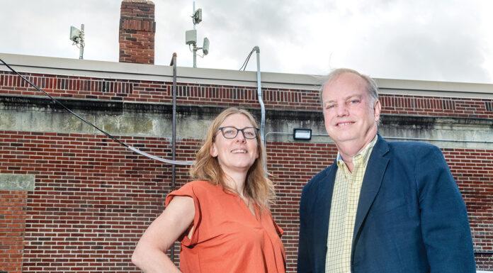 Jennifer Hawkins, left, CEO and president of the nonprofit ONE Neighborhood Builders, and David Marble, CEO and president of OSHEAN Inc., check new network antennae on the roof of ONE Neighborhood Builders’ Providence headquarters. The antennae are helping to provide free Wi-Fi to residents in the Olneyville neighborhood.  PBN PHOTO/­MICHAEL SALERNO
